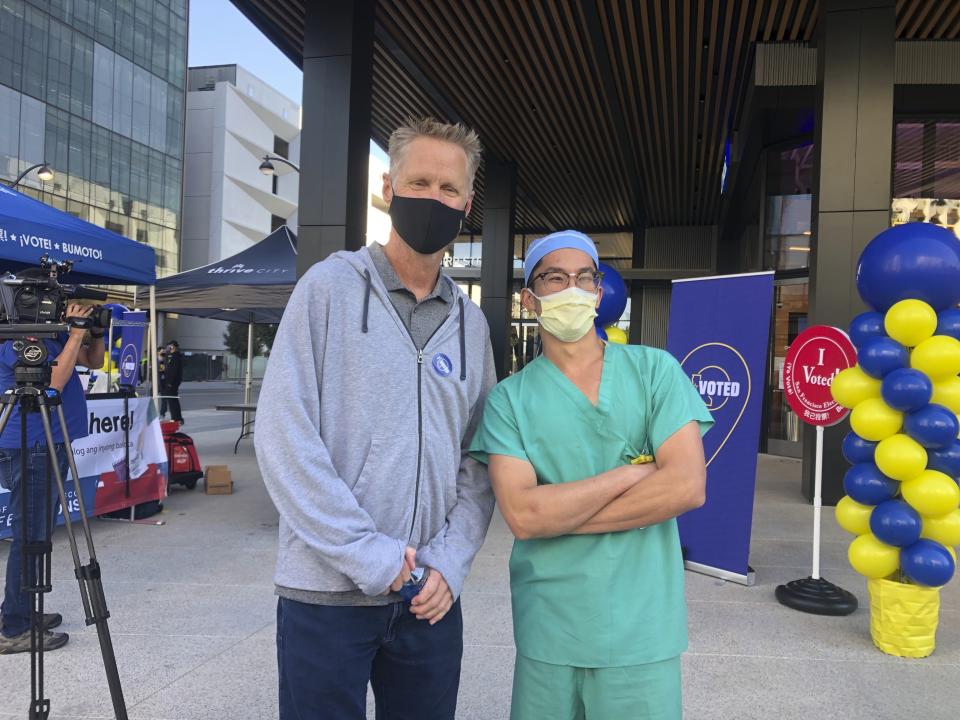 Golden State Warriors coach Steve Kerr poses with pharmacy technician Charles Dee by a ballot drop-off location at Chase Center on Saturday, Oct. 31, 2020, in San Francisco. (AP Photo/Janie McCauley)