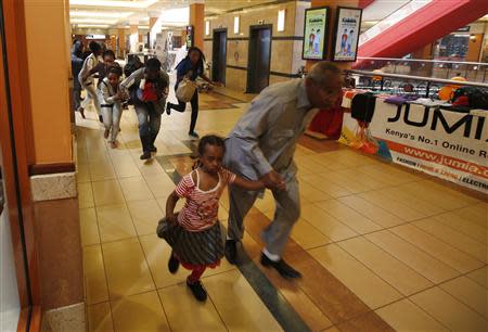 People with children run for safety as armed police hunt gunmen who went on a shooting spree at Westgate shopping centre in Nairobi, September 21, 2013. REUTERS/Goran Tomasevic