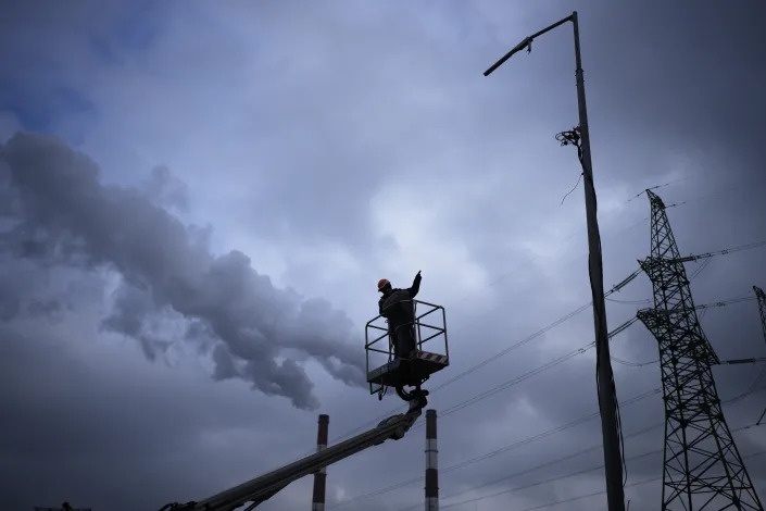 An electrical worker checks damage at a power plant after a rocket attack.