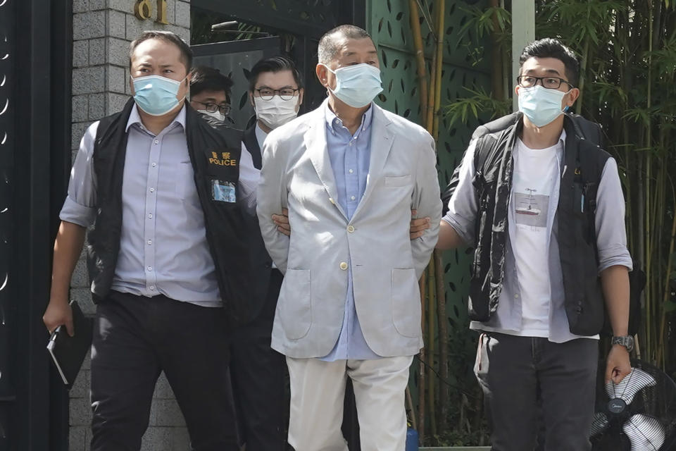 Hong Kong media tycoon Jimmy Lai, center, who founded local newspaper Apple Daily, is arrested by police officers at his home in Hong Kong, Monday, Aug. 10, 2020. Hong Kong police arrested Lai and raided the publisher's headquarters Monday in the highest-profile use yet of the new national security law Beijing imposed on the city after protests last year. (AP Photo)