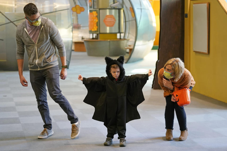 Grayson Martin, 3, poses in his costume as his parents Rachelle and Patrick Martin, look on, during a visit to Discovery Gateway Children's Museum on Thursday, Oct. 28, 2021, in Salt Lake City. Coronavirus cases in the U.S. are on the decline, and trick-or-treaters can feel safer collecting candy. (AP Photo/Rick Bowmer)