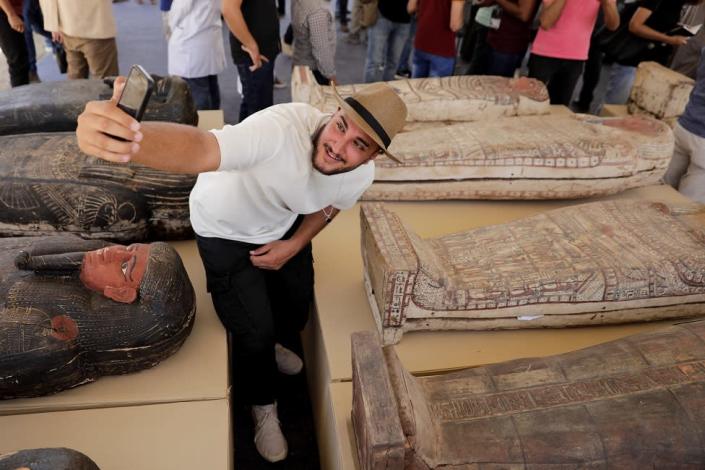 A man takes a selfie next to displayed sarcophaguses that are around 2500 years old, from the newly discovered burial site near Egypt&quot;s Saqqara necropolis, during a presentation in Giza, Egypt May 30, 2022.