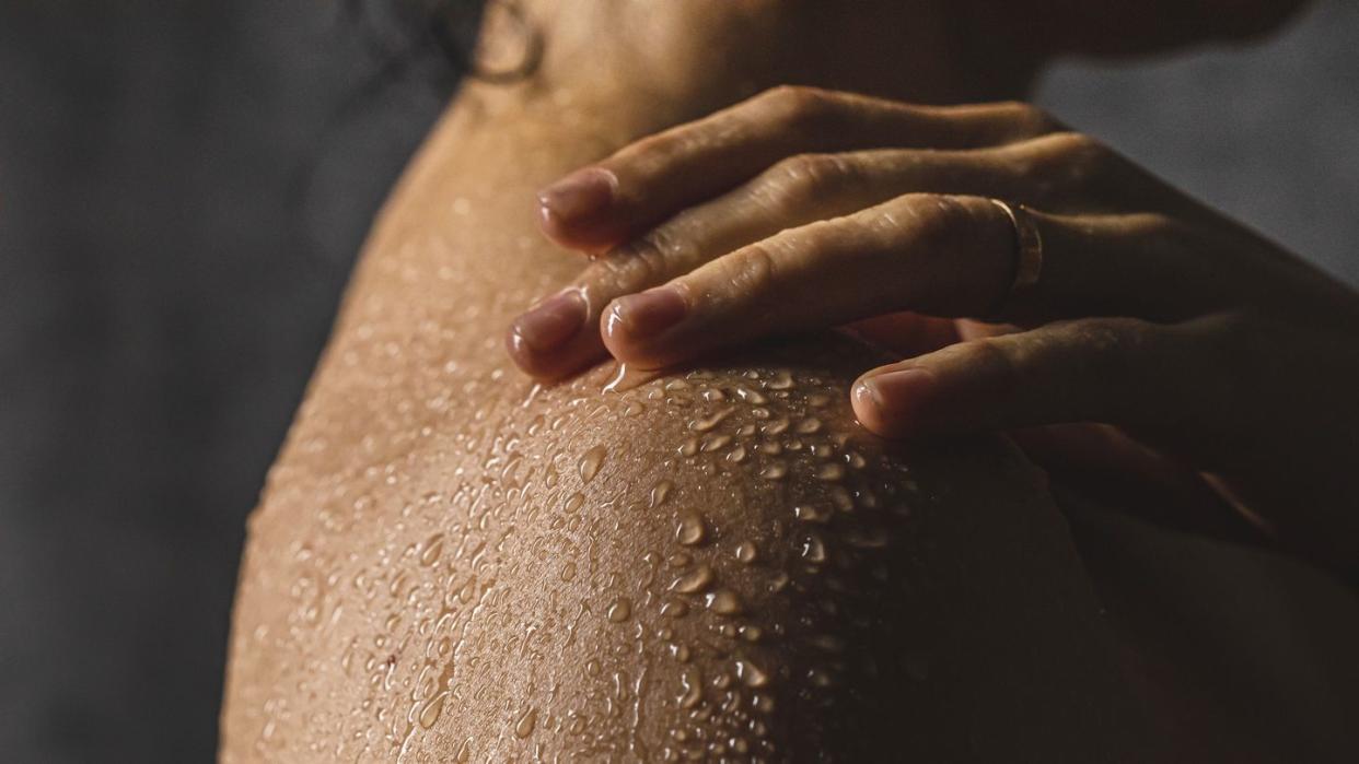 woman's shoulder with hand on shower