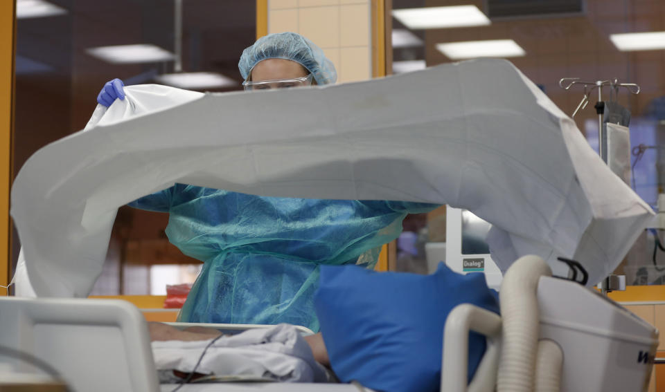 A healthcare worker attends to a COVID-19 patient at an intensive care unit (ICU) at the General University Hospital in Prague, Czech Republic, Tuesday, April 7, 2020. The new coronavirus causes mild or moderate symptoms for most people, but for some, especially older adults and people with existing health problems, it can cause more severe illness or death. (AP Photo/Petr David Josek)