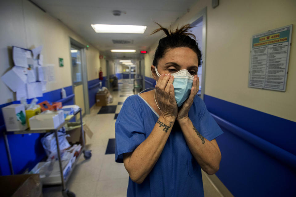 In this photo taken on Friday, April 10, 2020 nurse Cristina Settembrese fixes two masks to her face during her work shift in the COVID-19 ward at the San Paolo hospital in Milan, Italy. Settembrese spends her days caring for COVID-19 patients in a hospital ward, and when she goes home, her personal isolation begins by her own choice. (AP Photo/Luca Bruno)