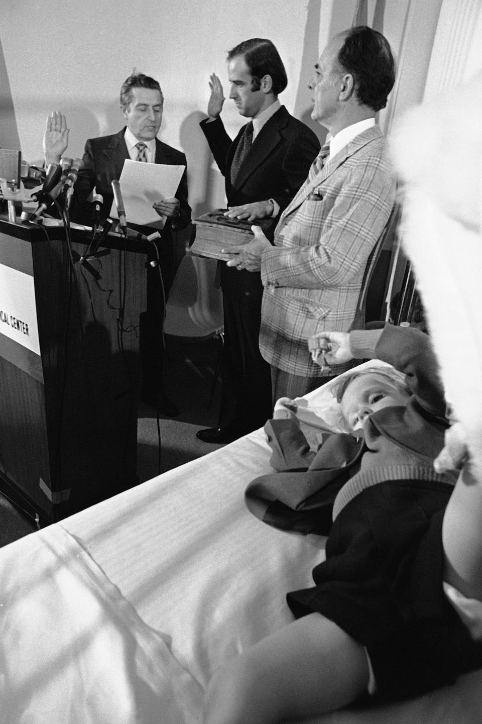 FILE - In this Friday, Jan. 5, 1973 file photo, four-year-old Beau Biden, foreground, watches his father, Joe Biden, center, being sworn in as the U.S. senator from Delaware, by Senate Secretary Frank Valeo, left, in ceremonies in a Wilmington hospital. Beau was injured in an accident that killed his mother and sister in December. Mrs. Biden's father, Robert Hunter, holds the Bible. (AP Photo/File)