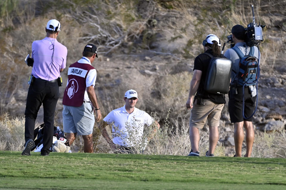 Patrick Cantlay, center, reviews his shot from the desert area off the 18th fairway during the final round of the Shriners Children's Open golf tournament, Sunday, Oct. 9, 2022, in Las Vegas. (AP Photo/David Becker)