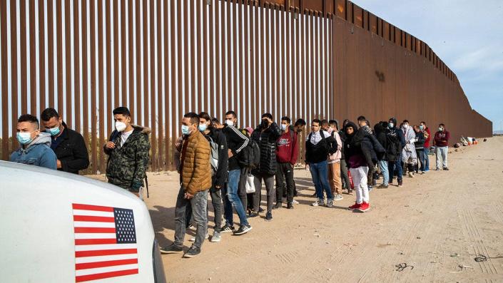 Immigrants are taken into custody by U.S. Border Patrol agents at the U.S.-Mexico border Dec. 7, 2021, in Yuma, Arizona. <span class="copyright">John Moore/Getty Images</span>