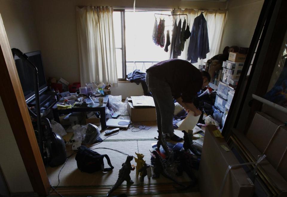 In this Thursday, May 1, 2014 photo, Kazuya Haraguchi, 45, a technician for film reel, looks for some items at his apartment filled with Godzilla collection in Tokyo. As Japan's film company Toho hasn’t made a Godzilla film for 10 years, “I hope the day will come when a Japanese director can make a Godzilla movie again for the world,” Haraguchi said. (AP Photo/Junji Kurokawa)