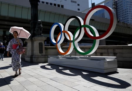 A woman wearing the yukata, or casual summer kimono, walks past Olympic rings displayed at Nihonbashi district in Tokyo