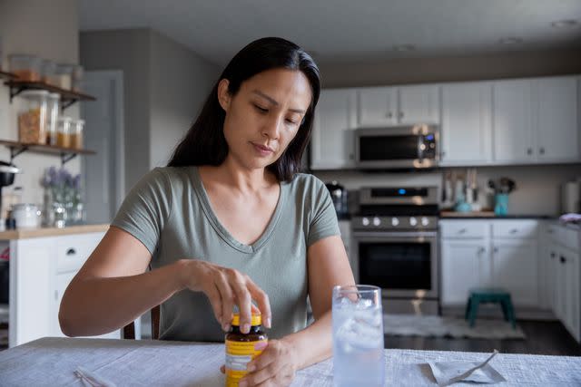 <p>Courtney Hale / Getty Images</p> Mature female opening a vitamin bottle