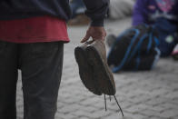 A Honduran migrant holds his shoes before starting to walk again as part of a caravan of hundreds of Honduran migrants making their way the U.S. in Esquipulas, Guatemala, early Tuesday, Oct. 16, 2018. U.S. President Donald Trump threatened on Tuesday to cut aid to Honduras if it doesn’t stop the impromptu caravan of migrants, but it remains unclear if governments in the region can summon the political will to physically halt the determined border-crossers. (AP Photo/Moises Castillo)