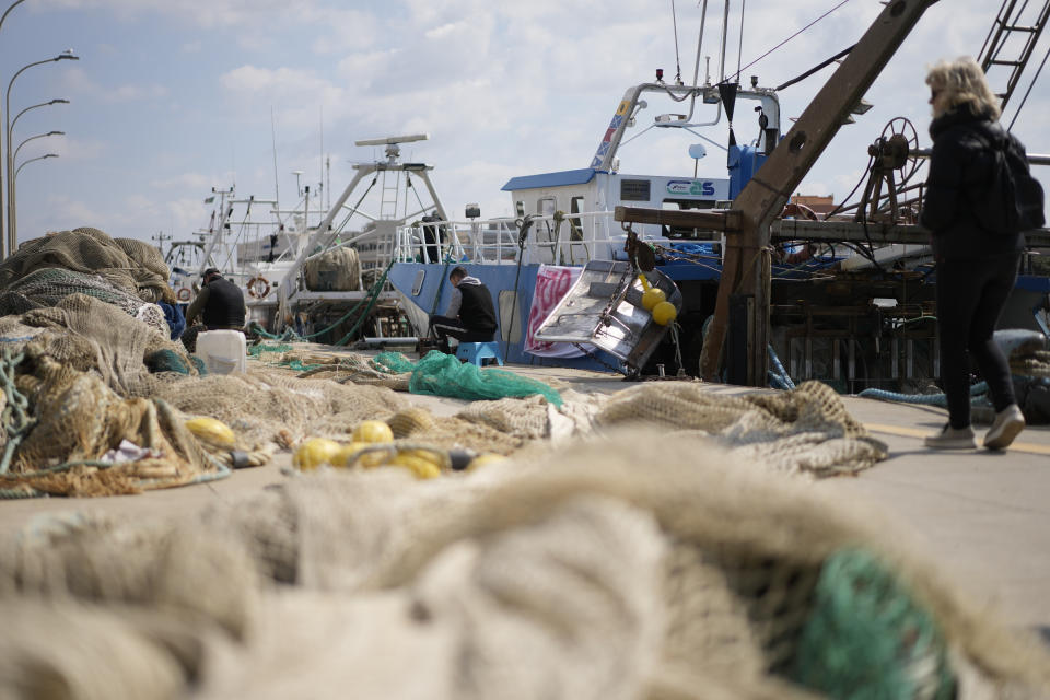 Fishermen mend nets in front of fishing boats at harbor in the Roman port of Fiumicino, Friday, March 11, 2022. Fishermen, facing huge spikes in oil prices, stayed in port, mending nets instead of casting them. Nowhere more than in Italy, the European Union’s third-largest economy, is dependence on Russian energy taking a higher toll on industry. (AP Photo/Andrew Medichini)