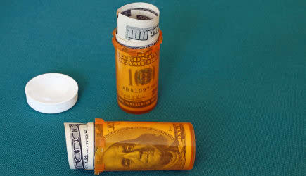 Symbolic presentation of the high cost of prescription medication. US $100 bills in pill containers.