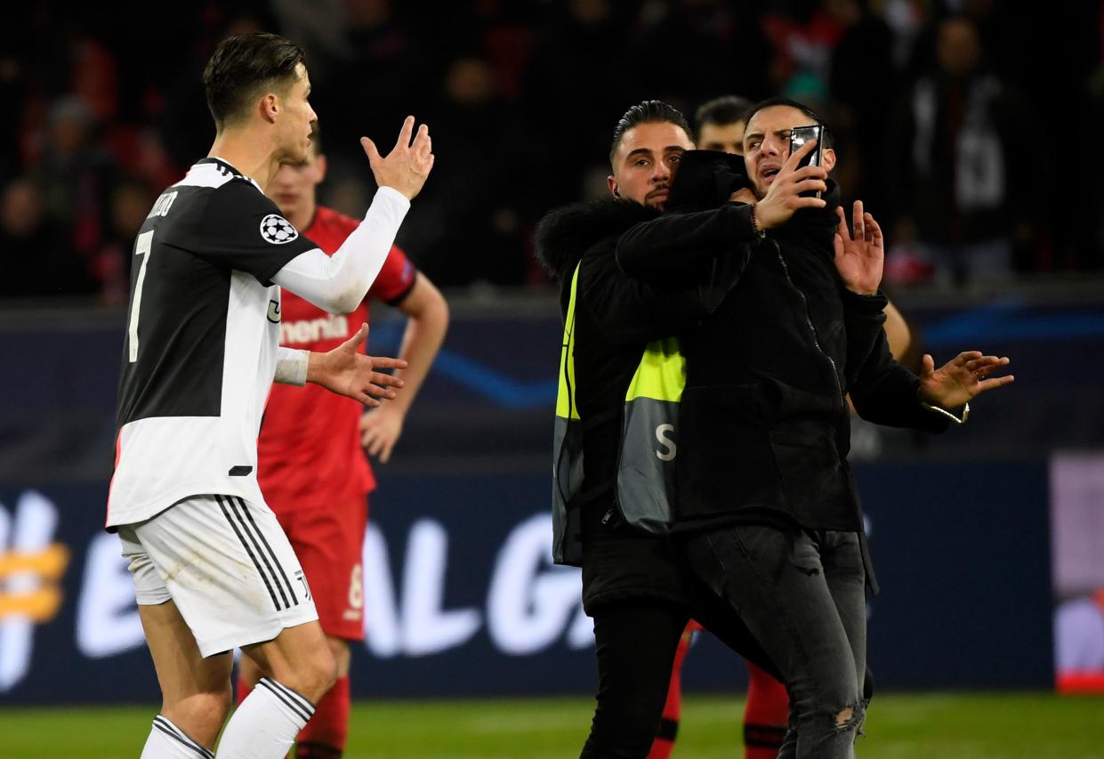 Juventus' Portuguese forward Cristiano Ronaldo (L) argues with a pitch invader after the UEFA Champions League Group D football match between Bayer Leverkusen and Juventus on December 11, 2019 in Leverkusen, western Germany. (Photo by INA FASSBENDER / AFP) (Photo by INA FASSBENDER/AFP via Getty Images)