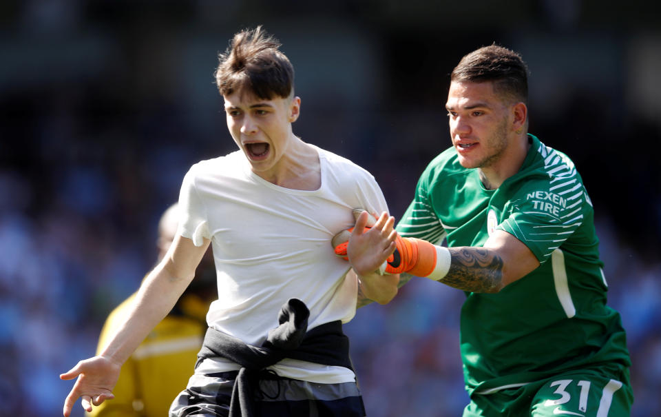 <p>Soccer Football – Premier League – Manchester City vs Huddersfield Town – Etihad Stadium, Manchester, Britain – May 6, 2018 Manchester City’s Ederson restrains a fan as he runs on the pitch after the end of the match Action Images via Reuters/Carl Recine EDITORIAL USE ONLY. No use with unauthorized audio, video, data, fixture lists, club/league logos or “live” services. Online in-match use limited to 75 images, no video emulation. No use in betting, games or single club/league/player publications. Please contact your account representative for further details. </p>