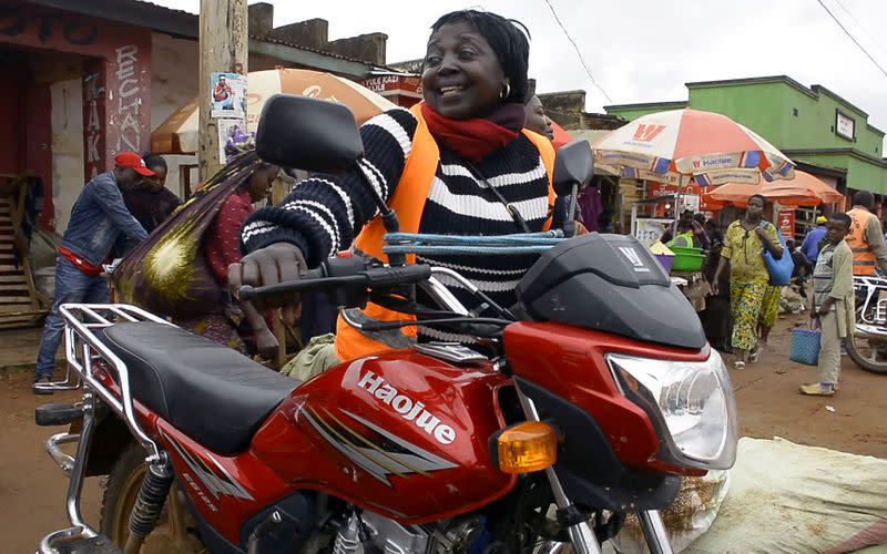 Congolese motorbike taxi rider Imelda Mmambu adjusts her motorbike as she waits for clients along the streets of Beni