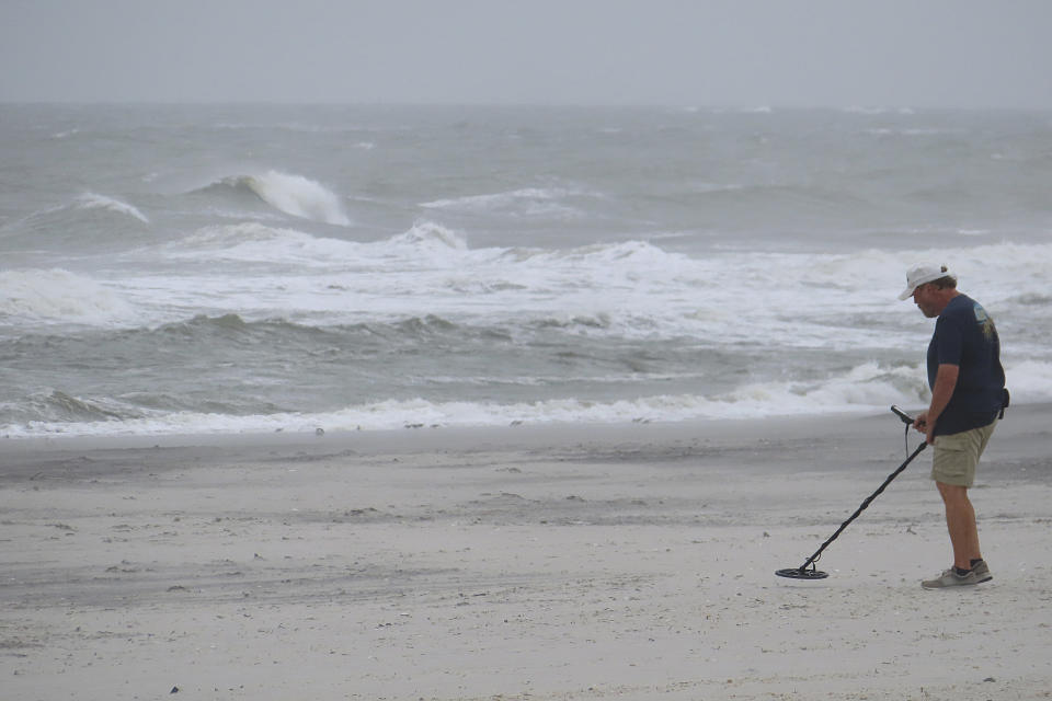 A man uses a metal detector on the beach during strong winds in Brigantine, N.J., on Wednesday, Sept. 18, 2024. (AP Photo/Wayne Parry)