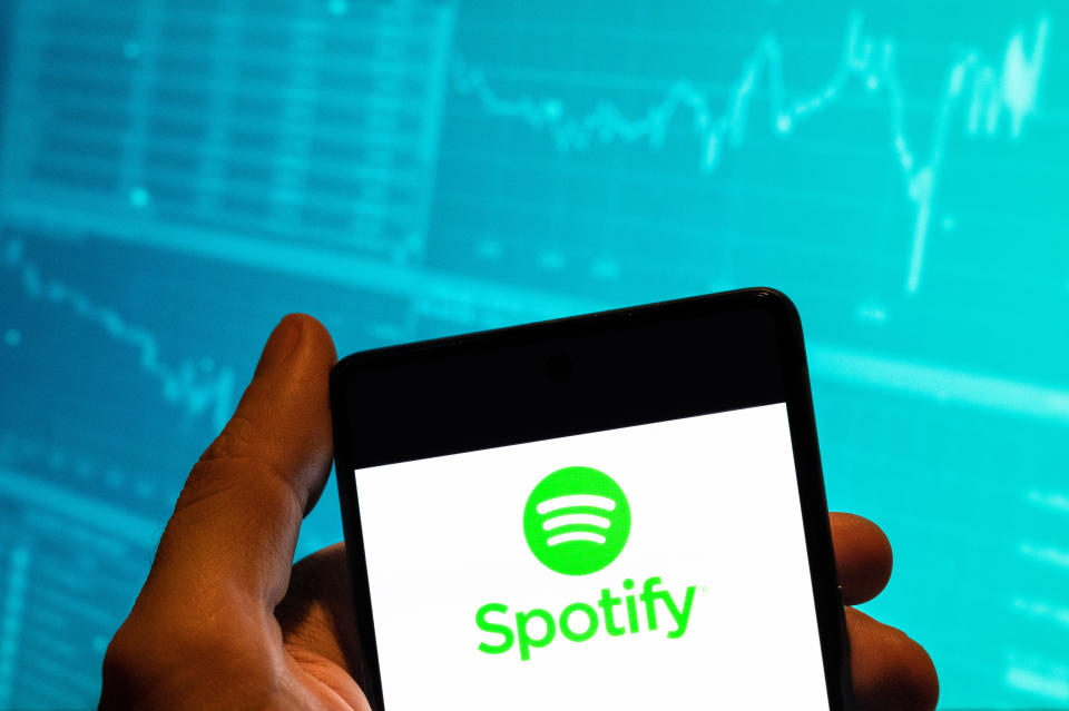 CHINA - 2023/02/15: In this photo illustration, the Swedish music streaming platform Spotify logo is seen displayed on a smartphone with an economic stock exchange index graph in the background. (Photo Illustration by Budrul Chukrut/SOPA Images/LightRocket via Getty Images)