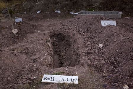 The grave of a young Iraqi, who drowned on August 27 at sea during an attempt to cross a part of the Aegean Sea from the Turkish coast, was exhumed on October 7 after his family traced him through DNA, at the Saint Panteleimon cemetery of Mytilene on the Greek island of Lesbos, October 7, 2015. REUTERS/Dimitris Michalakis