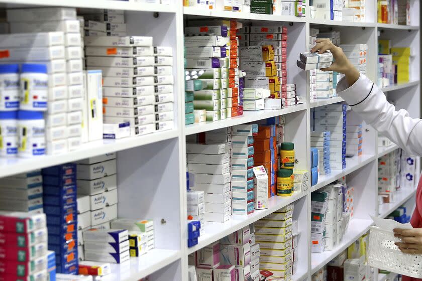 FILE - In this Nov. 5, 2018 file photo, a drugstore employee reaches for medicine from shelf in downtown Tehran, Iran. A cheap, daily pill that combines four drugs has been tested for the first time in the United States to see if it works as well among low-income Americans as it has in other countries to treat conditions leading to heart attacks and strokes. The results published Wednesday, Sept. 18, 2019, suggest the combo pill can lower blood pressure and bad cholesterol. Experts say the study may draw U.S. interest to a strategy that has been seen as useful only in places with limited access to medical care. (AP Photo/Ebrahim Noroozi, File)