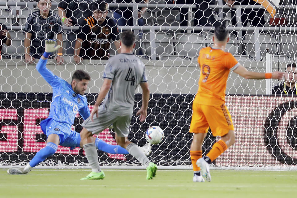 CF Montreal goalkeeper James Pantemis, left, misses a block on a goal by Houston Dynamo forward Sebastian Ferreira (9) as CF Montreal defender Rudy Camacho (4) looks on during the first half of an MLS soccer match Saturday, Aug. 13, 2022, in Houston. (AP Photo/Michael Wyke)