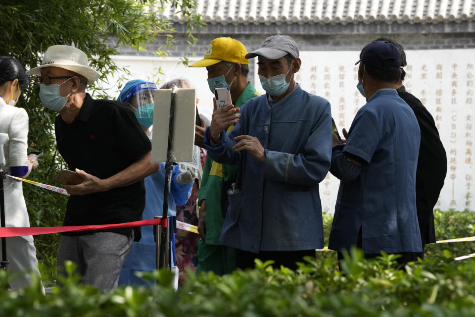 Residents wearing masks scan their health codes before lining up for sample COVID-19 test in Beijing, Tuesday, Aug. 30, 2022. (AP Photo/Ng Han Guan)