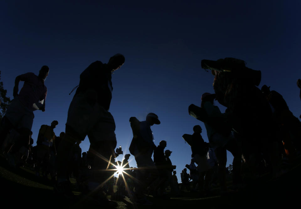 Spectators make their way down the first fairway at sunrise for the first round of the Masters golf tournament Thursday, April 10, 2014, in Augusta, Ga. (AP Photo/Matt Slocum)