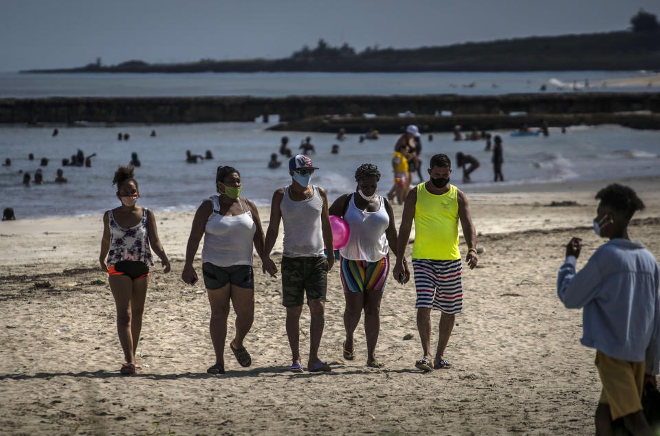 Personas que usan máscaras como precaución contra la propagación del nuevo coronavirus caminan en la playa en La Habana, Cuba, el domingo 11 de octubre de 2020. (AP Foto/Ramón Espinosa)