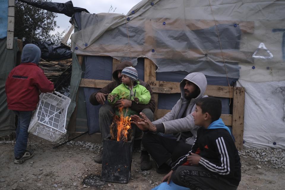 Migrants warm themselves outside the Moria refugee camp on the northeastern Aegean island of Lesbos, Greece, on Tuesday, Jan. 21, 2020. Some businesses and public services on the eastern Aegean island are holding a 24-hour strike on Wednesday to protest the migration situation, with thousands of migrants and refugees are stranded in overcrowded camps in increasingly precarious conditions.(AP Photo/Aggelos Barai)