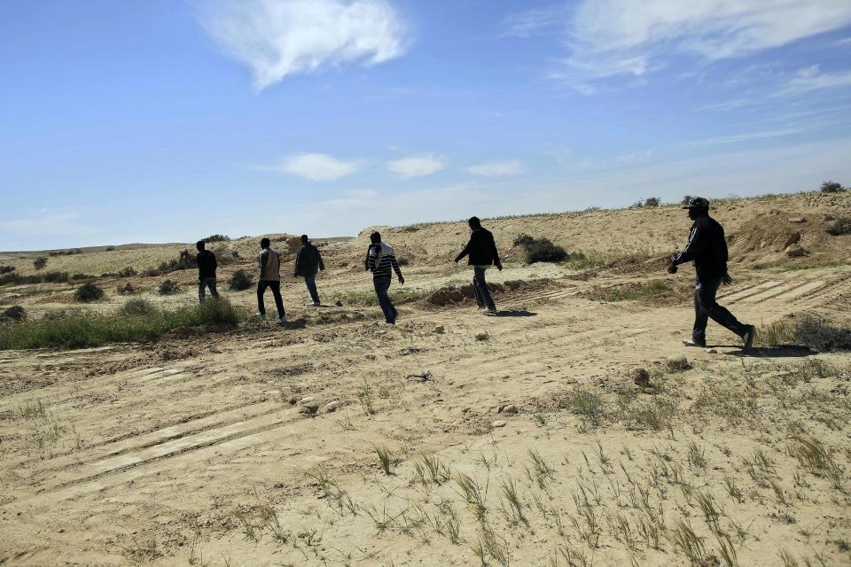 African migrants walk near the Holot detention center, southern Israel, Friday, April 11, 2014. Hundreds of African migrants gathered in Israel’s Negev desert on Friday to eat matzo and recall the Passover story - one of freedom from bondage - mere steps away from a detention facility where they are being held. The symbolic Passover seder, a festive meal to be held by Jews around the world Monday night, was organized to draw attention to the plight of Israel’s migrants, who themselves fled persecution and conflict, yet face detention under the country’s infiltrators law. (AP Photo/Tsafrir Abayov)