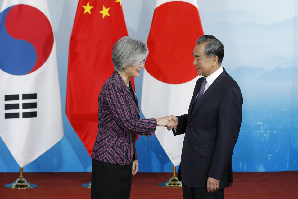Chinese Foreign Minister Wang Yi, right, shakes hands with his South Korean counterpart Kang Kyung-wha before a trilateral meeting with Japanese Foreign Minister Taro Kono at Gubei Town in Beijing Wednesday Aug. 21, 2019. (Wu Hong/Pool Photo via AP)