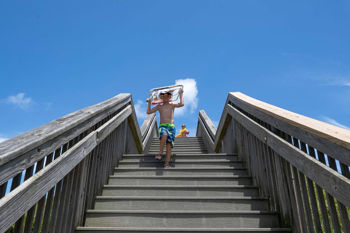 Camden Donai of Pittsburgh, Pa. carries his beach chair down the steps of a beach access point on Tuesday, June 29, 2021 in Nags Head, N.C. Robert Willett/rwillett@newsobserver.com