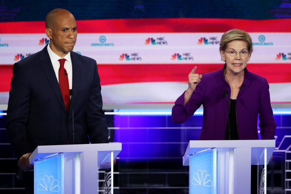 MIAMI, FLORIDA - JUNE 26: Sen. Elizabeth Warren (D-MA) speaks as Sen. Cory Booker (D-NJ) looks on during the first night of the Democratic presidential debate on June 26, 2019 in Miami, Florida.  A field of 20 Democratic presidential candidates was split into two groups of 10 for the first debate of the 2020 election, taking place over two nights at Knight Concert Hall of the Adrienne Arsht Center for the Performing Arts of Miami-Dade County, hosted by NBC News, MSNBC, and Telemundo. (Photo by Joe Raedle/Getty Images)