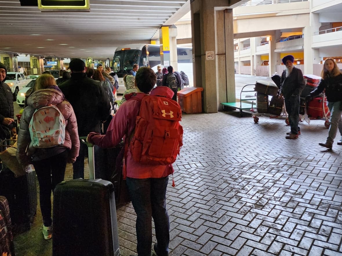 WestJet passengers line up to board a bus travelling from Calgary to Regina on Feb. 26.  (Gilbert Proulx/Twitter - image credit)