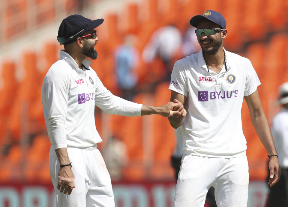 India's captain Virat Kohli, left, shares a light moment with teammate Axar Patel during the first day of fourth cricket test match between India and England at Narendra Modi Stadium in Ahmedabad, India, Thursday, March 4, 2021. (AP Photo/Aijaz Rahi)