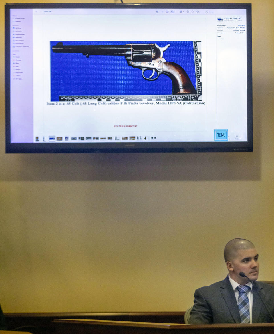 CORRECTION: REMOVES REFERENCE ABOUT OWNERSHIP OF GUN - FBI forensic examiner Bryce Ziegler looks at a picture of a firearm as he testifies during Hannah Gutierrez-Reed trial at District Court, Monday, Feb. 26, 2024, in Santa Fe, N.M. Gutierrez-Reed is charged with involuntary manslaughter and tampering with evidence in the October 2021 death of cinematographer Halyna Hutchins during the filming of the Western “Rust”. (Luis Sánchez Saturno/Santa Fe New Mexican via AP, Pool)