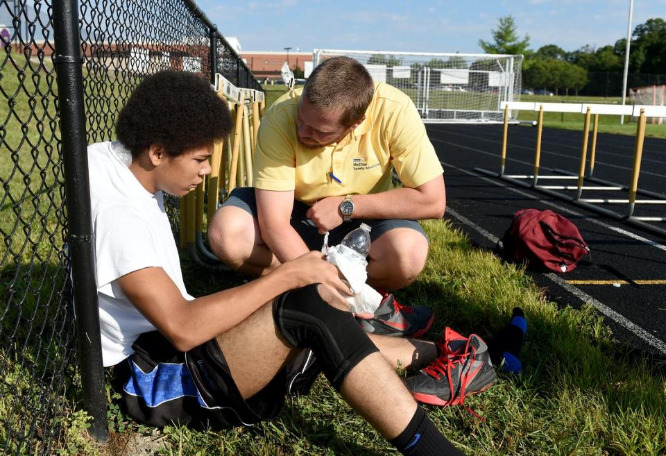 An athletic trainer helps a teenage football player who had trouble after running during August training at a Maryland high school. <a href="https://www.gettyimages.com/detail/news-photo/meade-high-athletic-trainer-jason-hickman-helps-jv-football-news-photo/453633426" rel="nofollow noopener" target="_blank" data-ylk="slk:Jonathan Newton / The Washington Post via Getty Images;elm:context_link;itc:0;sec:content-canvas" class="link ">Jonathan Newton / The Washington Post via Getty Images</a>