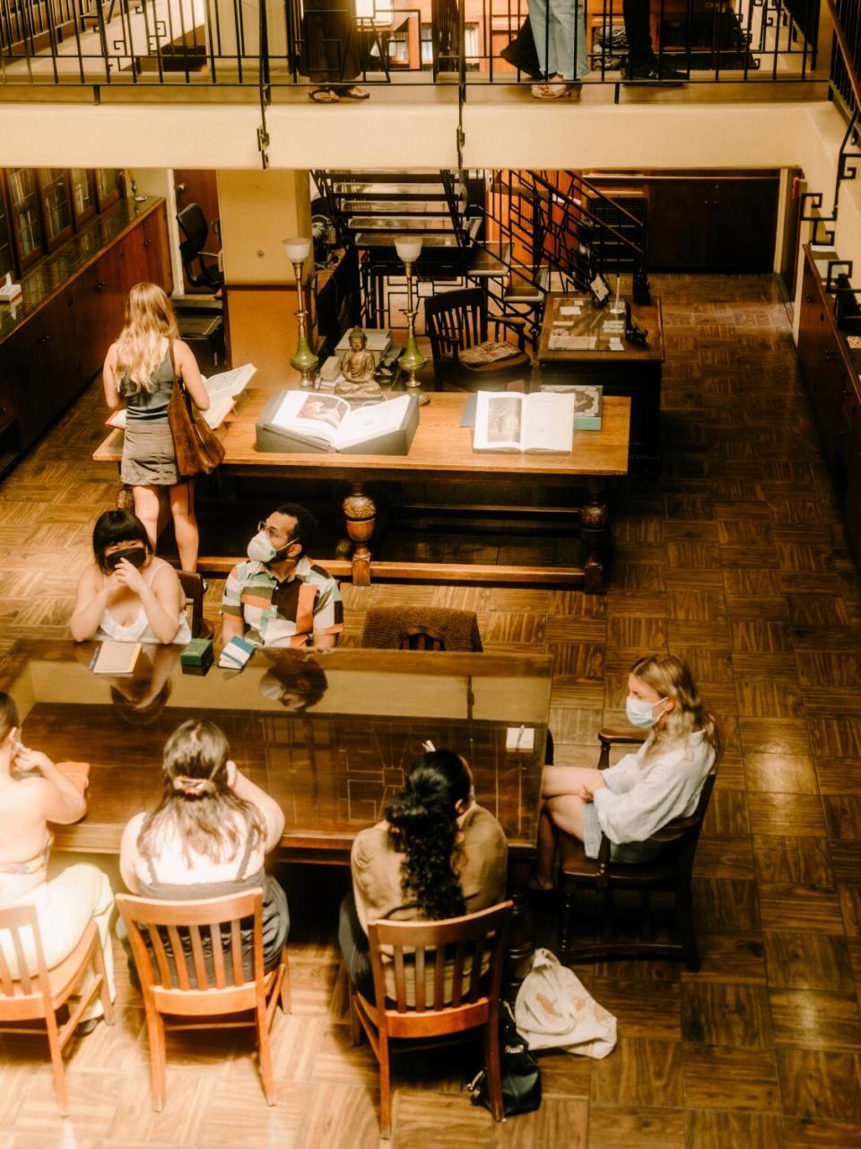 A view from above of people seated at wooden tables in a library