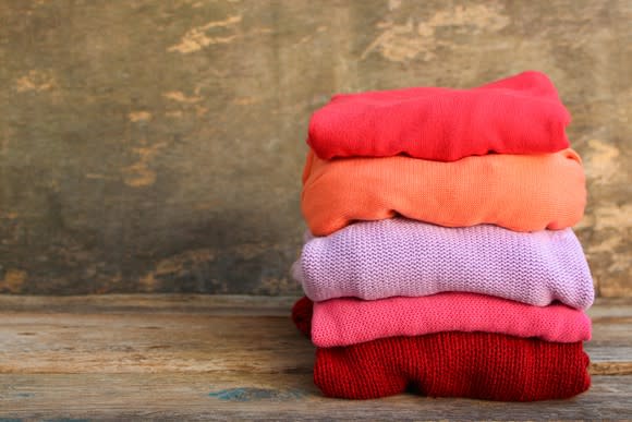 A folded pile of colorful clothes against a brown background