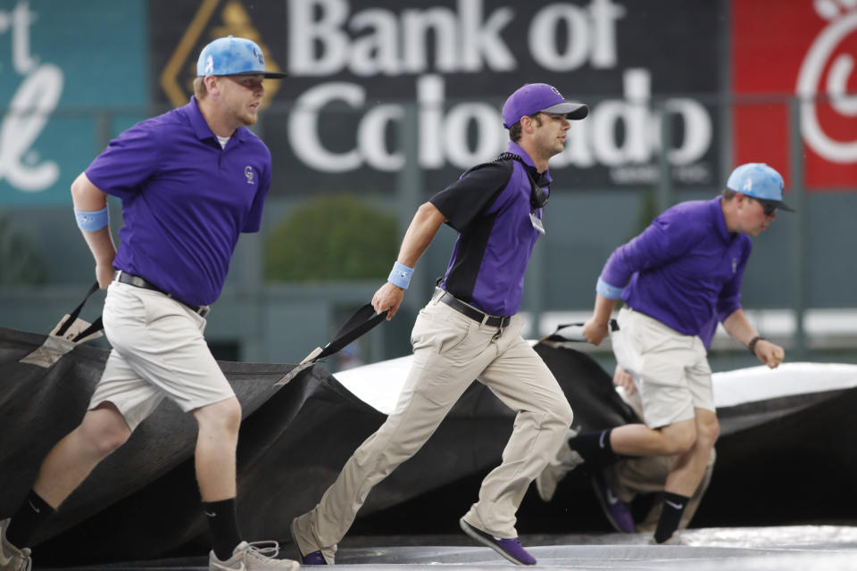 Grounds crew members pull the tarpaulin during a lightning and rain delay in the sixth inning of a baseball game between the San Diego Padres and the Colorado Rockies, Sunday, June 16, 2019, in Denver. (AP Photo/David Zalubowski)