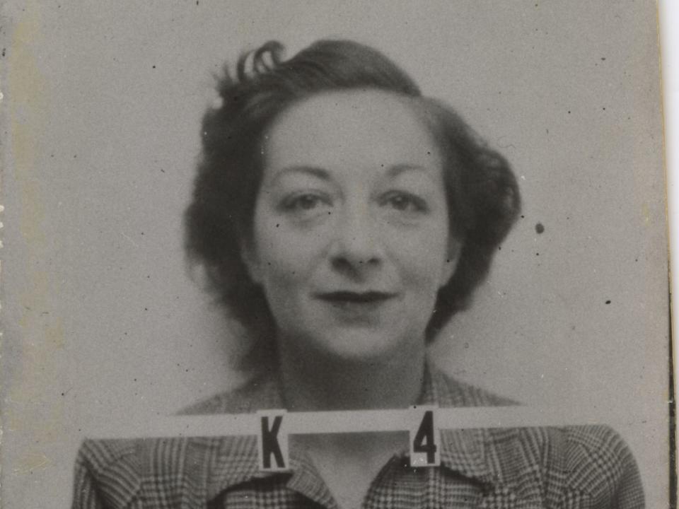 Charlotte Serber smiles in her badge photo for the Los Alamos laboratory with the alphanumero K 4 in front of her and her signature at the top