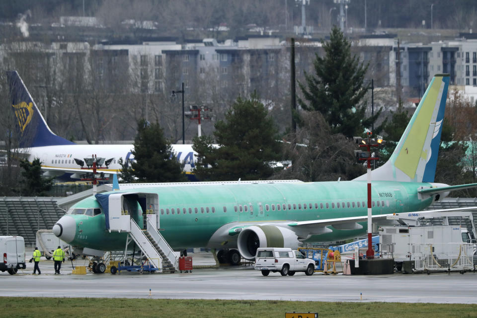 FILE - In this Dec. 11, 2019, file photo workers walk near a Boeing 737 Max airplane being built for Oman Air at Renton Municipal Airport in Renton, Wash. On Monday, Dec. 16, shares of Boeing are falling before the opening bell on a report that the company may cut production of its troubled 737 Max or even end production all together. (AP Photo/Ted S. Warren, File)