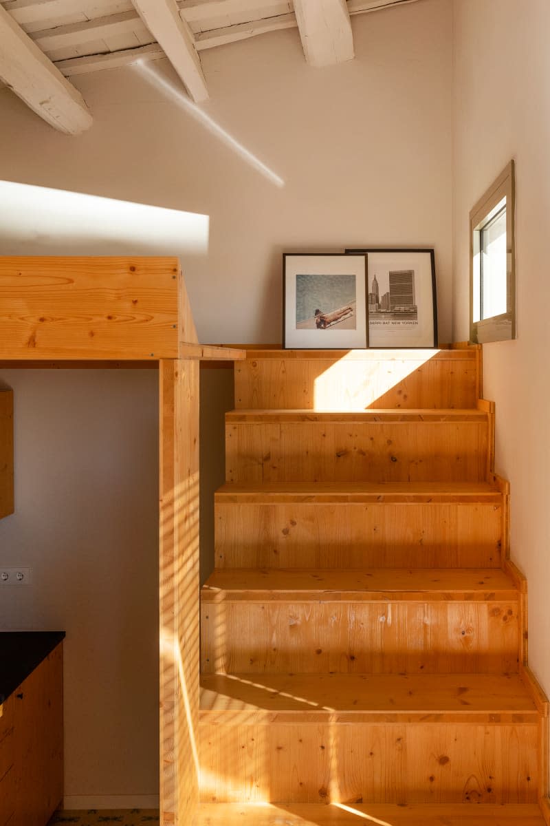 small white apartment with wood stairs leading up to loft space