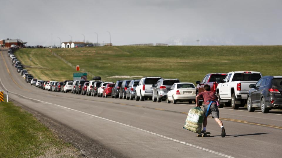 <span class="caption">An entrepreneur who can’t vote: A teenaged boy uses a skateboard to move up and down selling popcorn to southern Alberta residents lining up to get COVID-19 vaccines in May 2021.</span> <span class="attribution"><span class="source">THE CANADIAN PRESS/Jeff McIntosh</span></span>