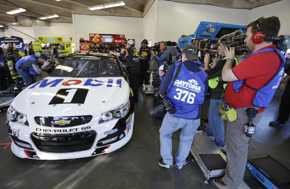 Photographers surround driver Tony Stewart's car as he gets ready to go out on the track to practice for the Sprint Unlimited auto race at Daytona International Speedway in Daytona Beach, Fla., Friday, Feb. 14, 2014. Stewart has not raced in more than six months since he broke two bones in his leg in an August sprint-car crash. (AP Photo/John Raoux)