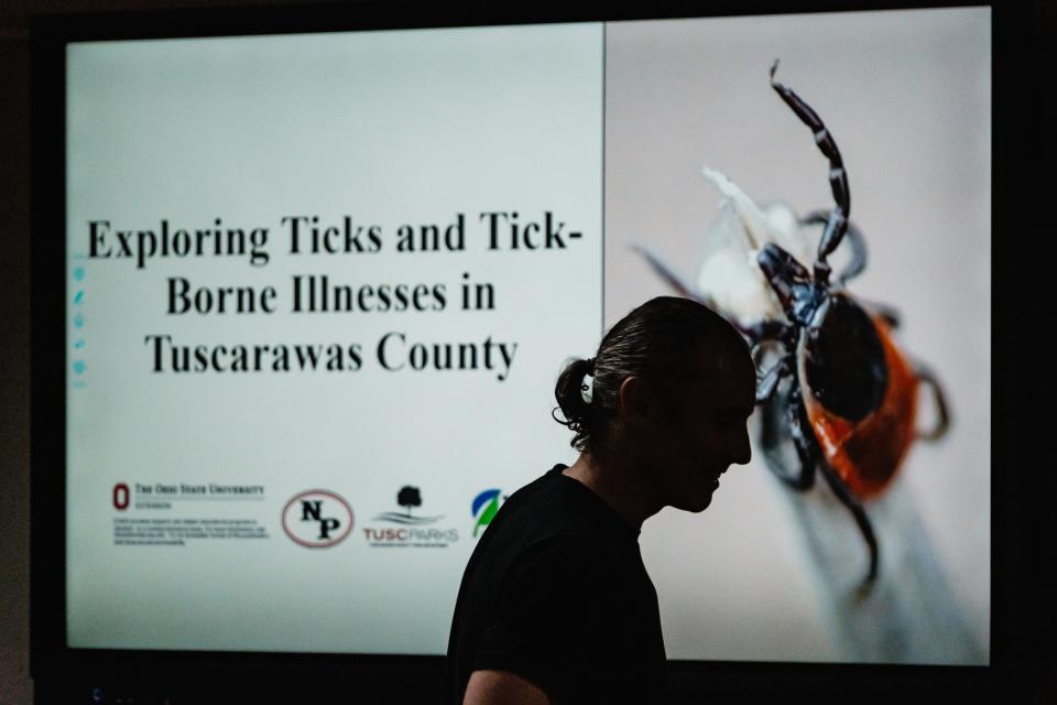 Kip Brady, a science teacher of 25 years at New Philadelphia High School, is silhouetted against the presentation screen shortly before the start of a special program on ticks.