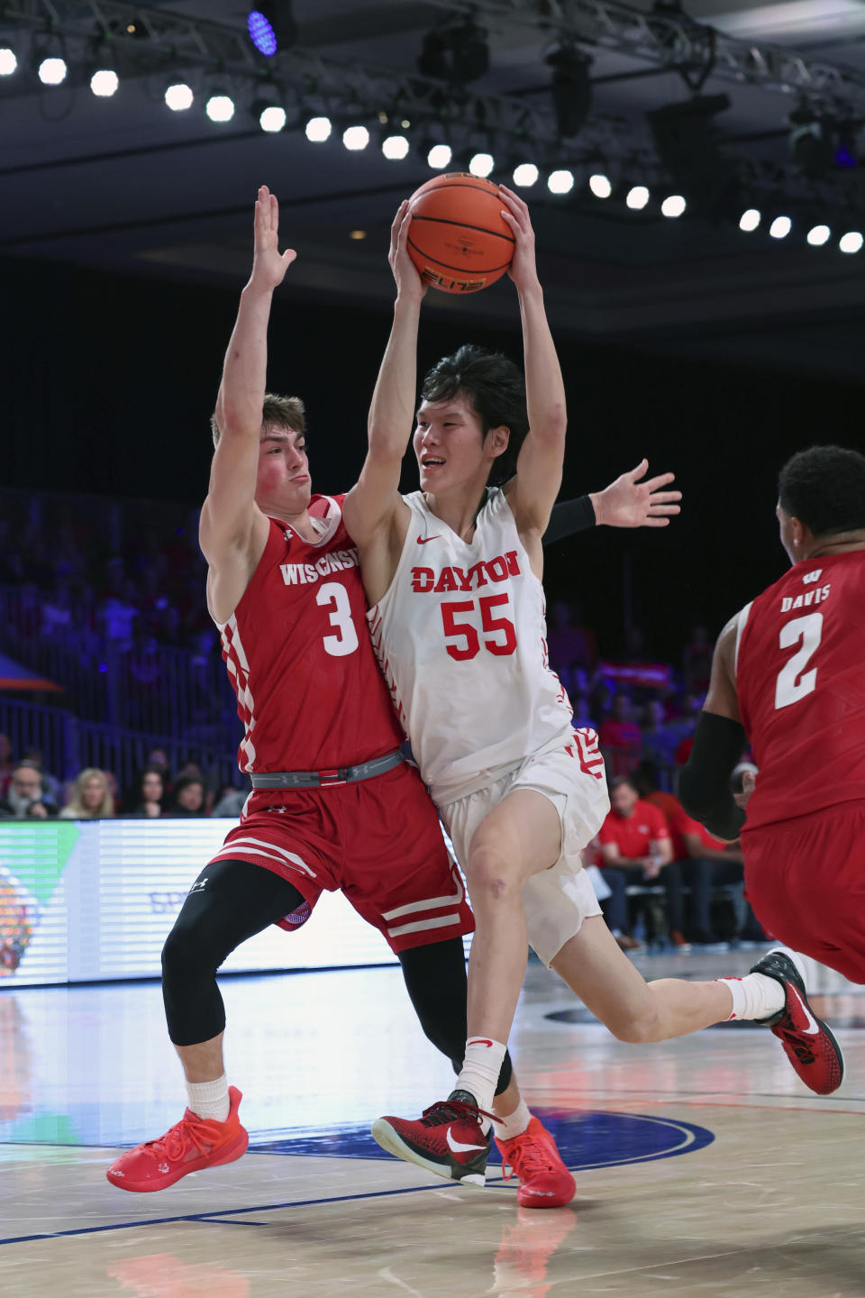 This photo provided by Bahamas Visual Services shows Dayton guard Mike Sharavjamts (55) driving against Wisconsin guard Connor Essegian (3) during an NCAA college basketball game at the Battle 4 Atlantis at Paradise Island, Bahamas, Wednesday, Nov. 23, 2022. . (Tim Aylen/Bahamas Visual Services via AP)