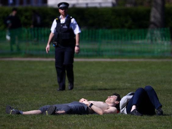 A police officer approaches a sunbather in Greenwich Park, south London. (REUTERS)