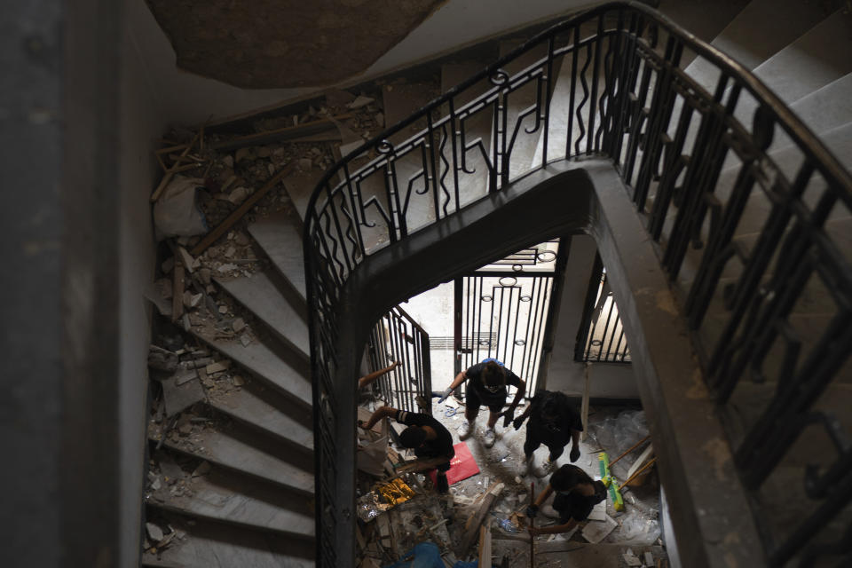 People remove debris of a damaged building at a neighborhood near the scene of Tuesday's explosion that hit the seaport of Beirut, Lebanon, Friday, Aug. 7, 2020. Rescue teams were still searching the rubble of Beirut's port for bodies on Friday, nearly three days after a massive explosion sent a wave of destruction through Lebanon's capital. (AP Photo/Felipe Dana)